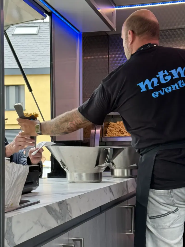 Medewerker van MTM Event schept vers gebakken friet