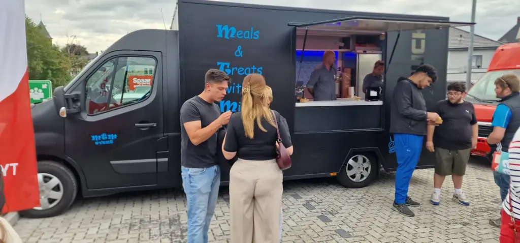 Gasten bij de zwarte foodtruck van MTM Event op een evenement